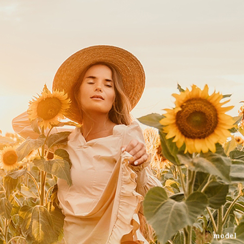 Woman with glowing skin  in field of sunflowers.